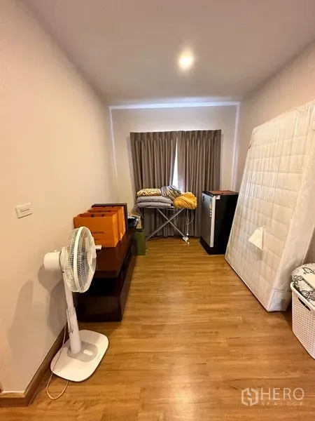Detached House for sale in Prawet, Bangkok - Spare room with wooden flooring, curtained window, fan and storage items.