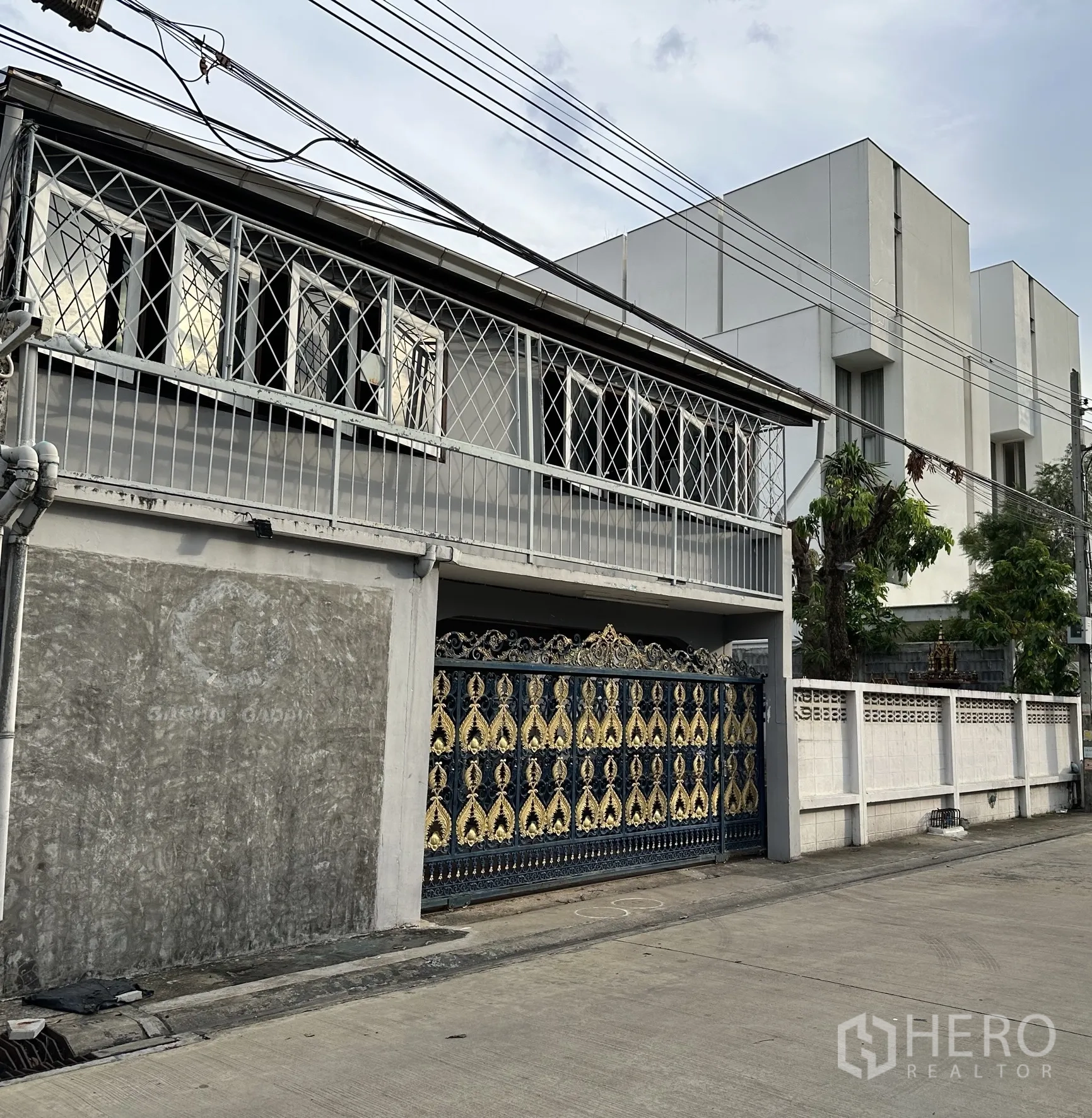 Home Office for rent in Suan Luang, Bangkok - Side view of the facade showing ornate blue and gold gate and window grilles.