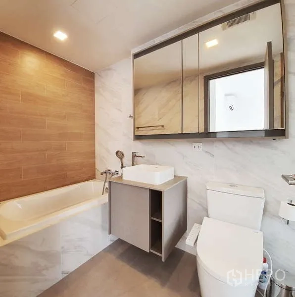 Condominium for sale in Watthana, Bangkok - Bathroom with bathtub, warm wall tiles, mirrored cabinets and a vanity.
