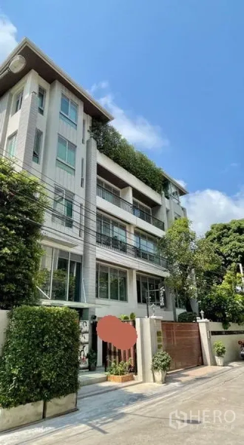办公空间 出租在Khlong Toei, Bangkok - 现代低层办公楼外观，设有阳台与绿植，入口配安全大门，蓝天下景致。