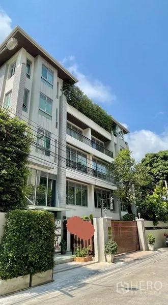 Office Space for rent in Khlong Toei, Bangkok - Modern low-rise office building exterior with balconies, greenery and a secure gate under a blue sky.