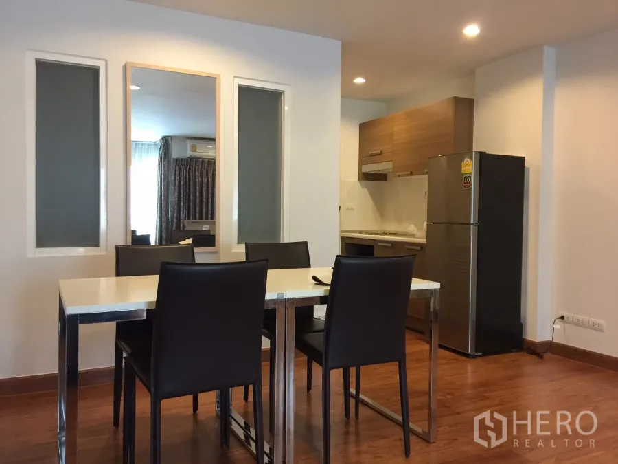Condominium for rent in Bang Rak, Bangkok - Open-plan dining and kitchenette with wood cabinets, stainless refrigerator, and recessed lighting.