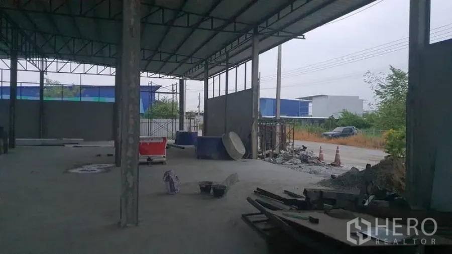 Warehouse for rent in Khlong Sam Wa, Bangkok - Warehouse loading area opening toward the roadside frontage with materials on the slab.