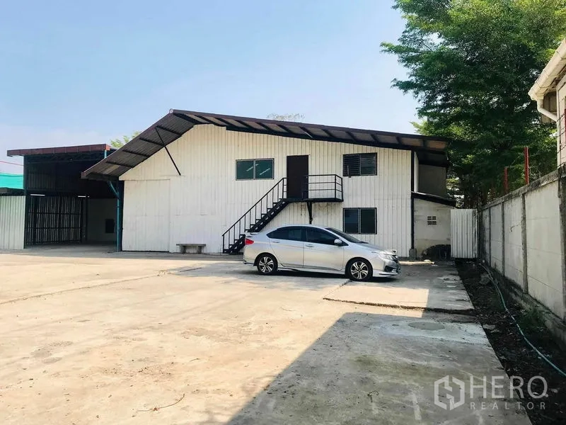 货栈 出租在Pathum Thani - 仓库外观，宽阔硬化场地、停车位及外置楼梯，Rangsit。