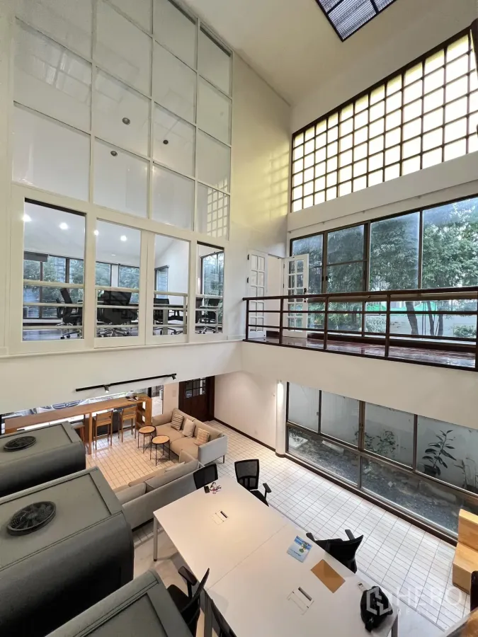 Townhouse for rent in Watthana, Bangkok - Loft-style atrium with floor-to-ceiling windows, lounge seating and work tables facing the garden.