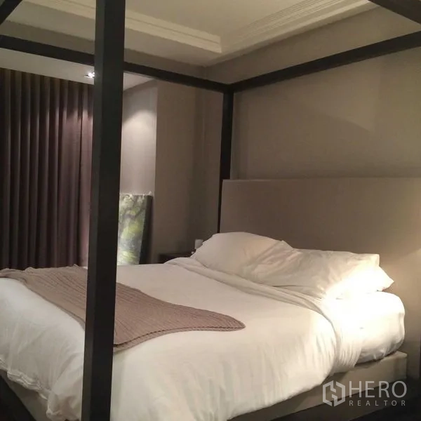 Condominium for sale in Pathum Wan, Bangkok - Primary bedroom with four-poster bed, upholstered headboard and soft ambient lighting.