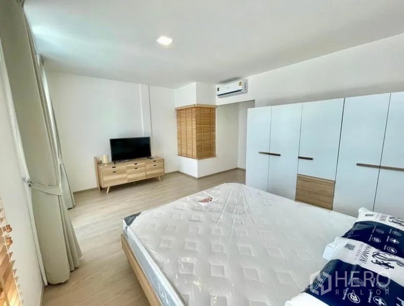 联排别墅 出租在Prawet, Bangkok - 宽敞主卧，配衣柜、电视柜与空调。