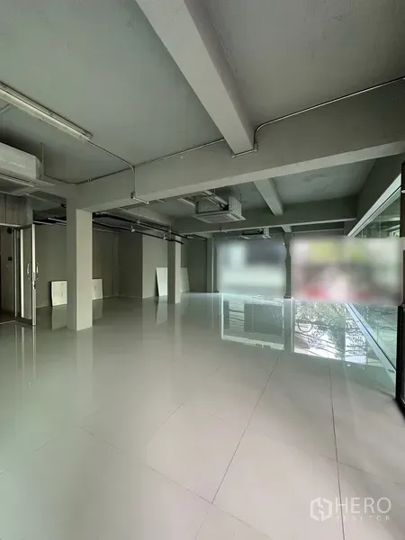 Retail Space for rent in Bang Rak, Bangkok - Open-plan retail interior with polished white tile floors, exposed ceiling ducting, and large windows.