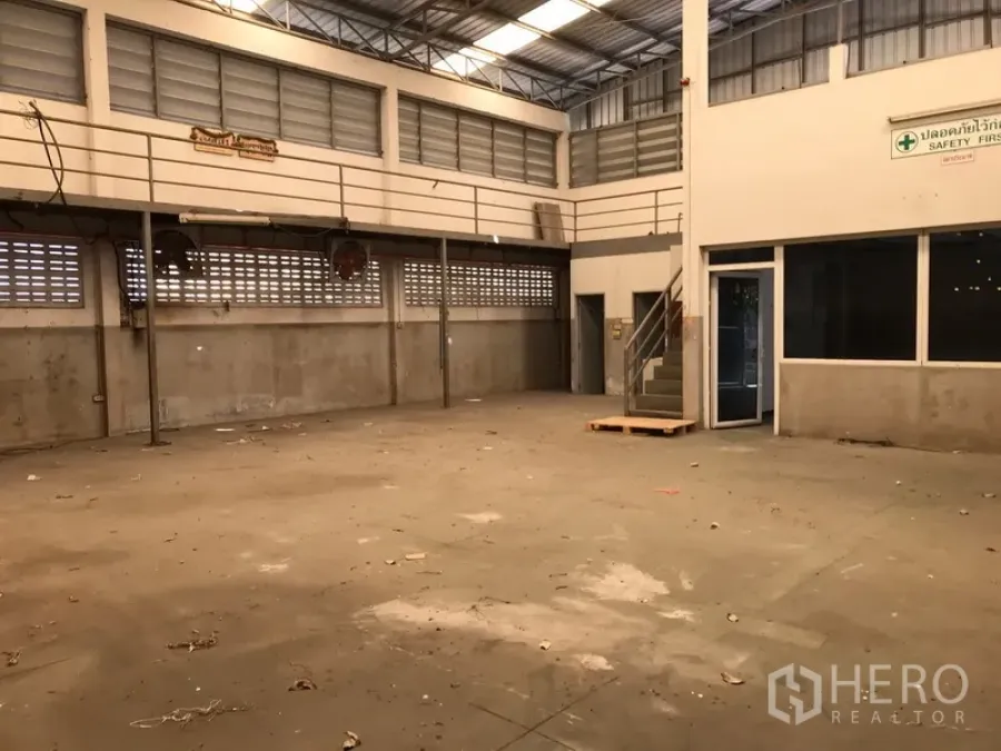 Warehouse for rent in Mueang Samut Prakan, Samut Prakan - Spacious warehouse interior with high ceiling, mezzanine walkway and a glass-walled office corner.