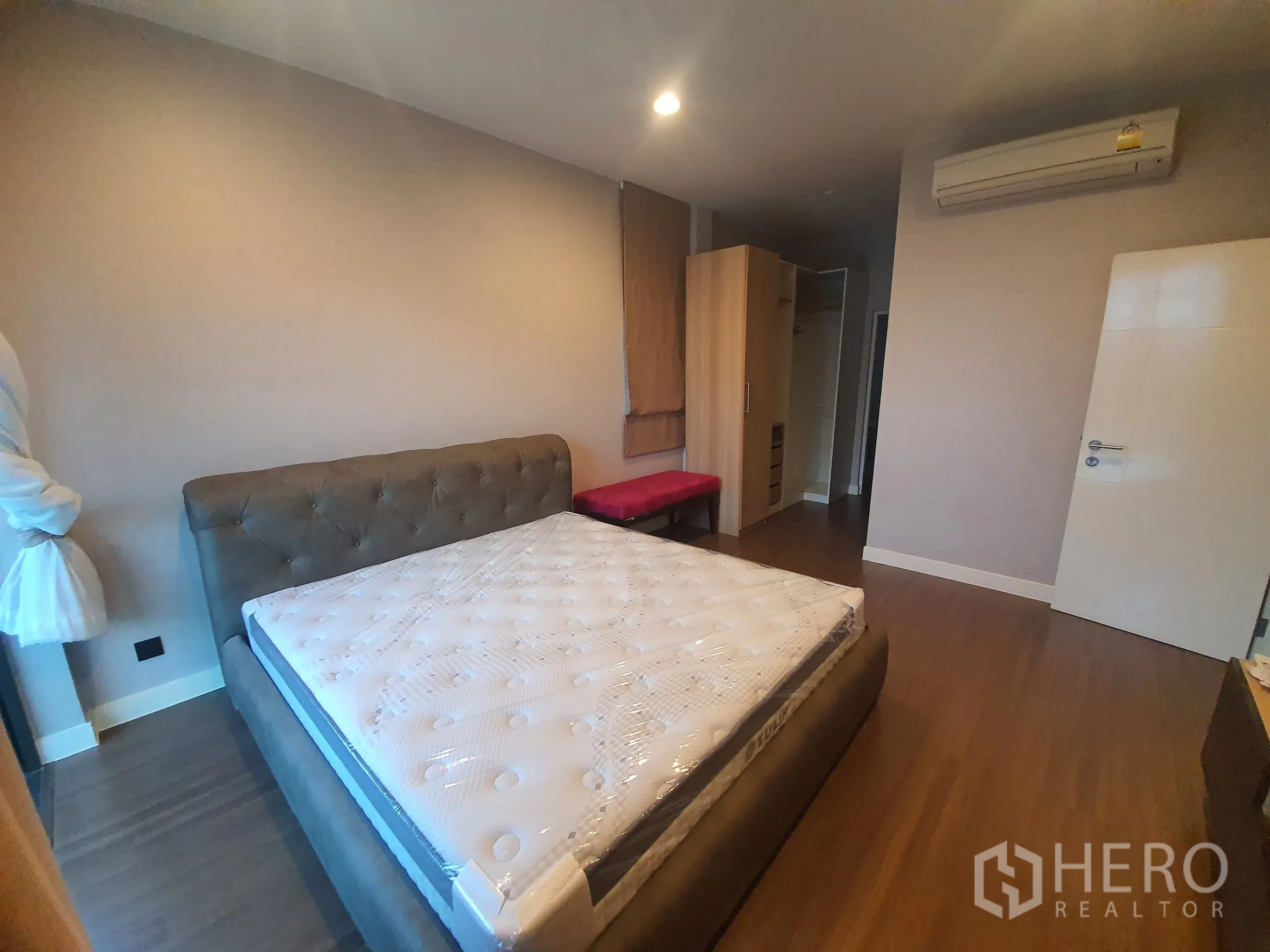 Detached House for rent in Bang Kapi, Bangkok - Air-conditioned bedroom with wood floors and upholstered bed frame.