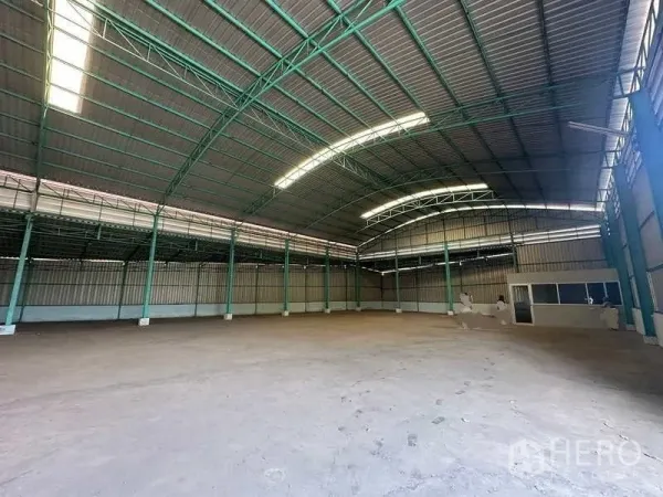 Warehouse for rent in Phra Nakhon Si Ayutthaya - Open storage floor with skylights, steel truss roof, and a corner office enclosure.