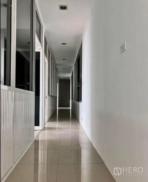 Warehouse for rent in Prawet, Bangkok - Clean tiled corridor lined with glass-partitioned office rooms.