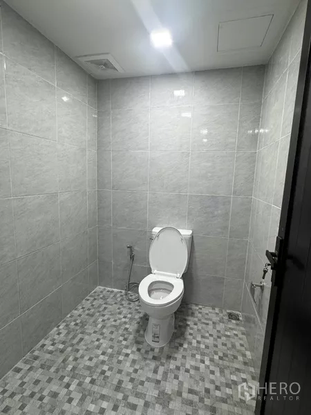 Shophouse for rent - Newly tiled bathroom with toilet and ceiling lighting inside the commercial building.