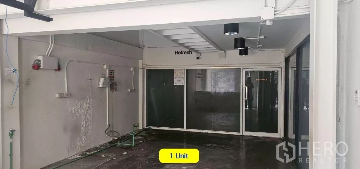 Shophouse for rent in Watthana, Bangkok - Ground-level space with glass partitions, spotlight fixtures, and an under-stair area.