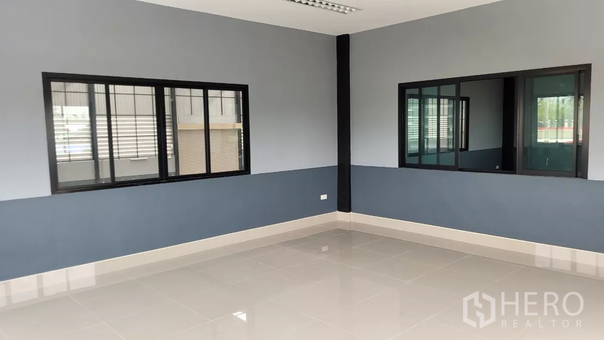 Factory for rent or sale in Phanat Nikhom, Chon Buri - Clean tiled office room with windows overlooking the warehouse floor.
