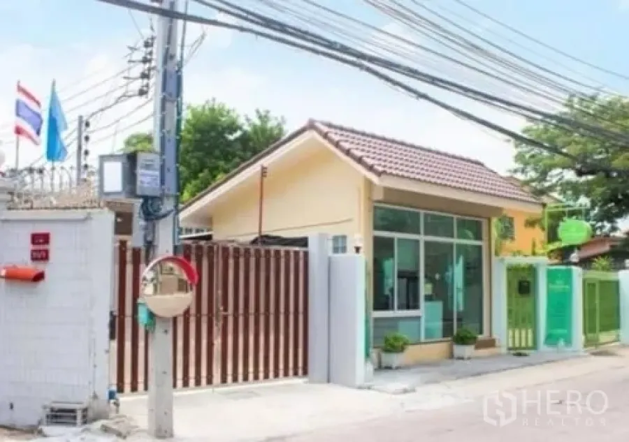 Townhouse for rent in Khlong Toei, Bangkok - Gated neighborhood entrance and guardhouse on a quiet city lane.