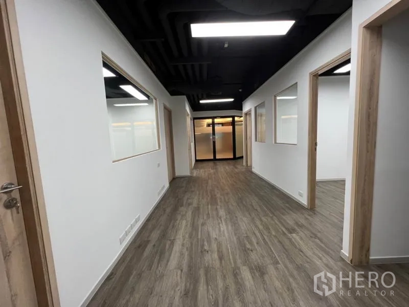 Office Space for rent in Khlong Toei, Bangkok - Long hallway inside the unit with multiple rooms and glass panels toward the entrance.