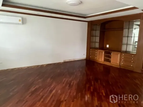 Townhouse for rent in Watthana, Bangkok - Spacious room with polished wood floors and built-in display and storage cabinets.