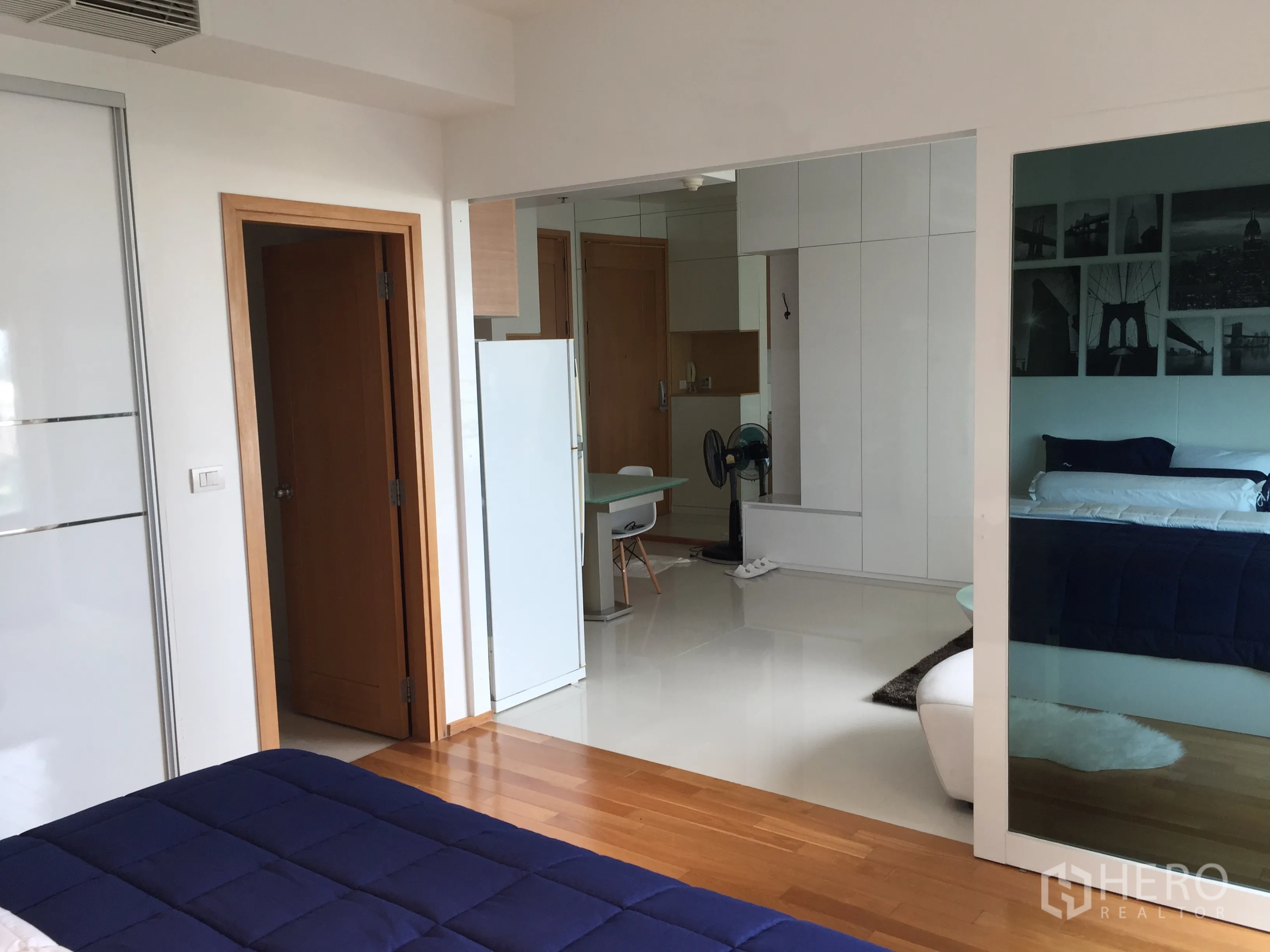 Condominium for rent in Khlong Toei, Bangkok - Bedroom view toward living room through sliding glass partition, hardwood floors and built‑in storage.