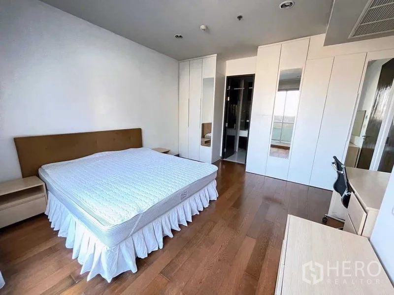 Condominium for rent in Pathum Wan, Bangkok - Master bedroom with king bed, built-in wardrobes with mirrors and desk.