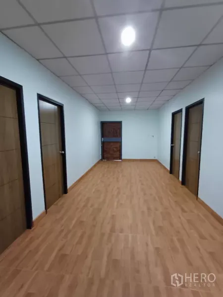 带办公室的家 出租在Phra Khanong, Bangkok - 明亮走廊，方格吊顶，多扇木门。