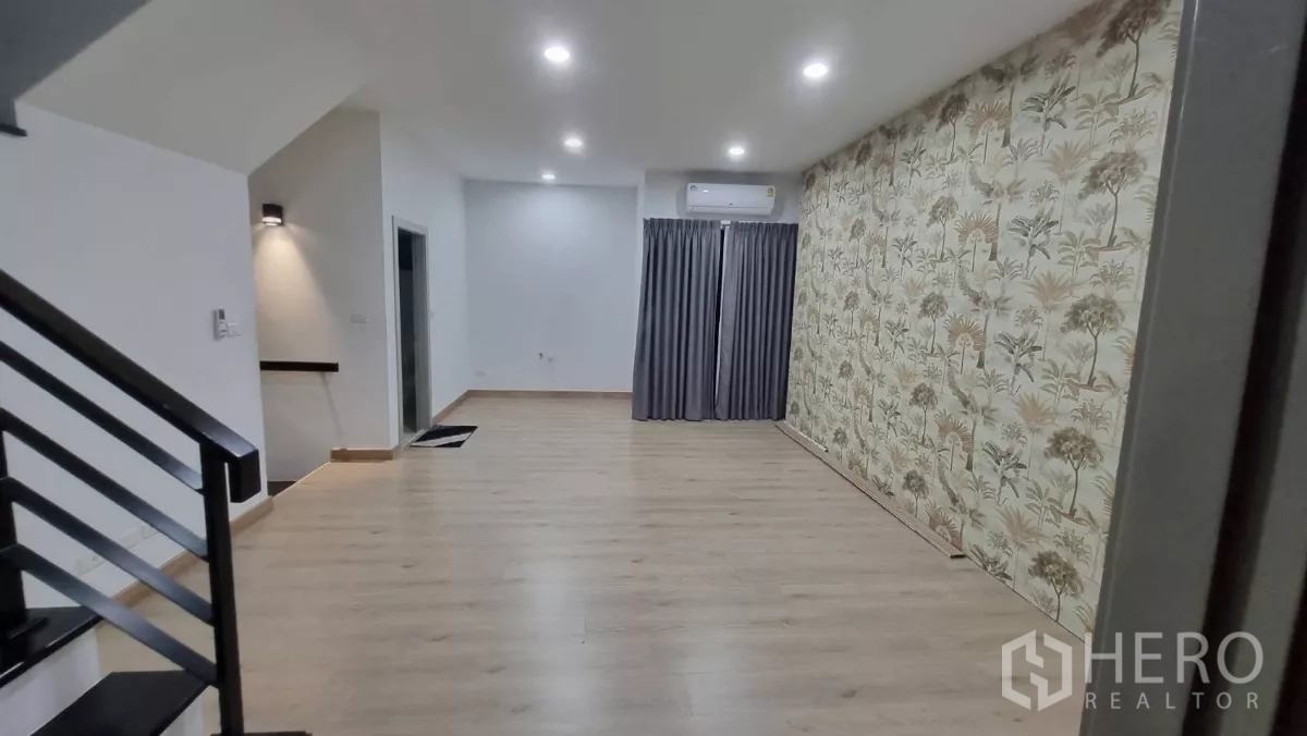 Home Office for rent in Lat Phrao, Bangkok - Spacious living or workspace with feature tropical wallpaper, recessed lighting and stair access.