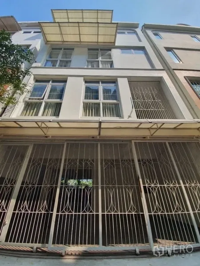 联排别墅 出租在Phaya Thai, Bangkok - 多层联排别墅外立面，带金属安防栅栏、大窗户和有顶车位。