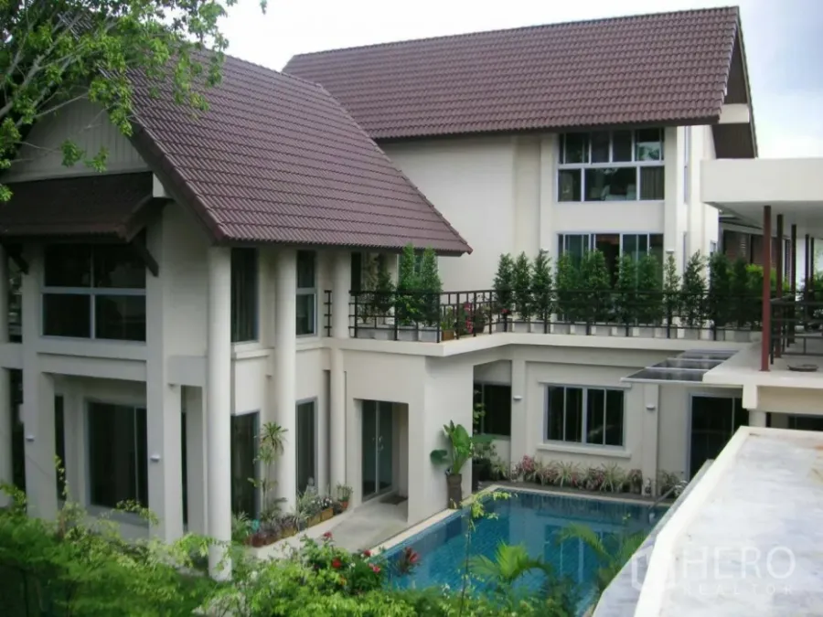 Detached House for rent or sale in Prawet, Bangkok - Contemporary detached house exterior with pitched tile roofs, large windows and a courtyard overlooking a swimming pool and greenery.