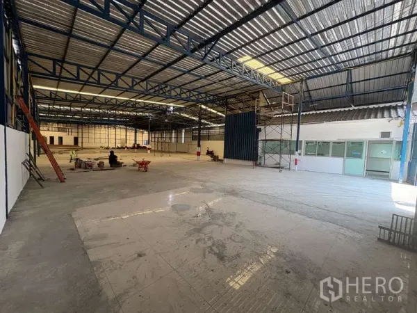 Warehouse for rent in Prawet, Bangkok - Open warehouse floor with high ceilings, steel columns, scaffolding, and side offices suitable for truck loading access.
