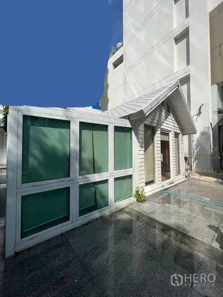 Retail Space for rent in Watthana, Bangkok - Corner view of glass-panel extension and gabled unit next to a high-rise