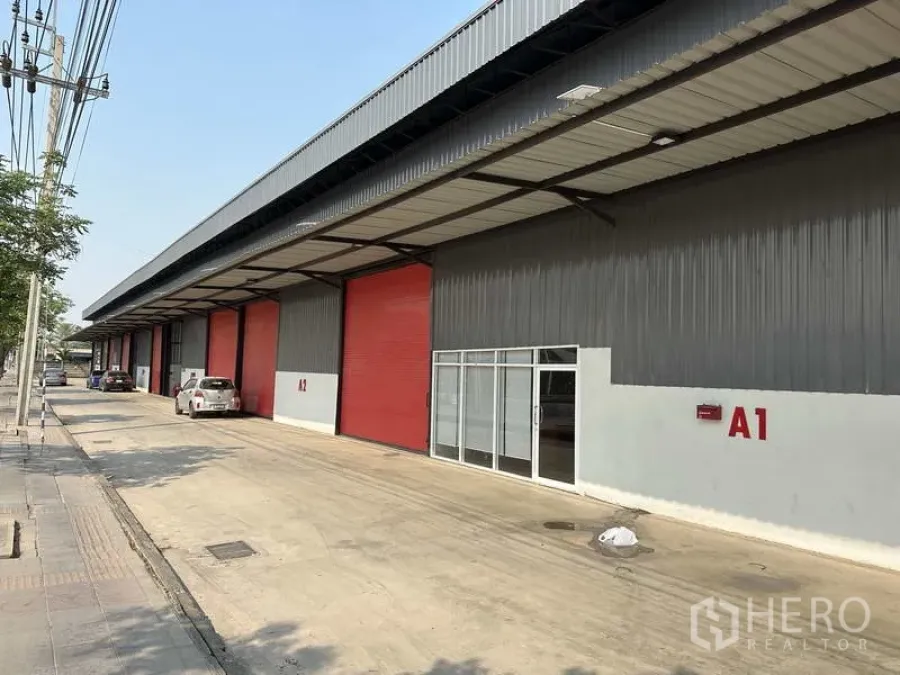 Warehouse for rent in Khlong Sam Wa, Bangkok - Modern warehouse row in Khlong Sam Wa with red roller doors, glass office entry, and a wide covered loading area.