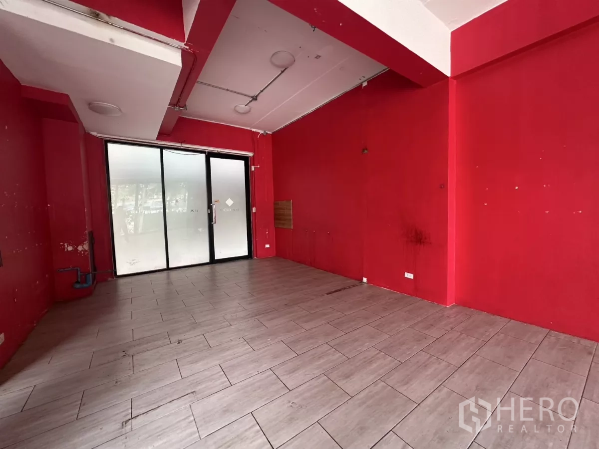 Retail Space for rent in Khlong Toei, Bangkok - Ground-floor retail unit with red walls, gray tile flooring and a frosted glass sliding entrance.