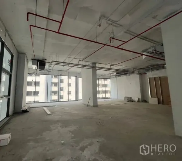 Retail Space for rent in Khlong Toei, Bangkok - Large corner retail floor plate with columns, exposed services and expansive full-height windows on two sides.
