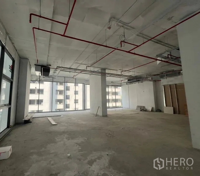Retail Space for rent in Khlong Toei, Bangkok - Large corner retail floor plate with columns, exposed services and expansive full-height windows on two sides.