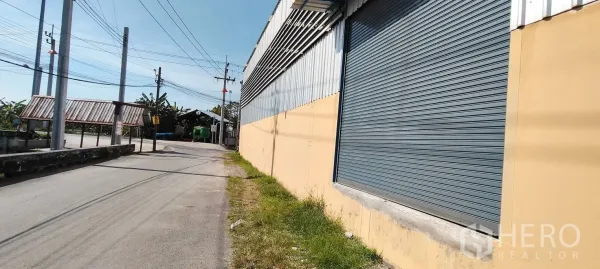 Warehouse for rent in Bang Phli, Samut Prakan - Street-side view of the warehouse exterior with a large metal roller shutter.