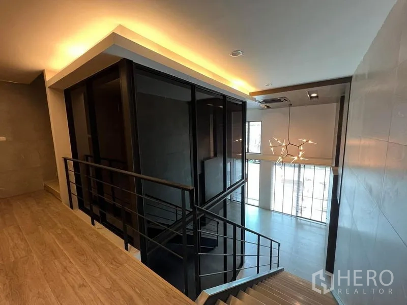 Home Office for rent in Bueng Kum, Bangkok - Stair landing overlooking double-height lobby and modern chandelier.