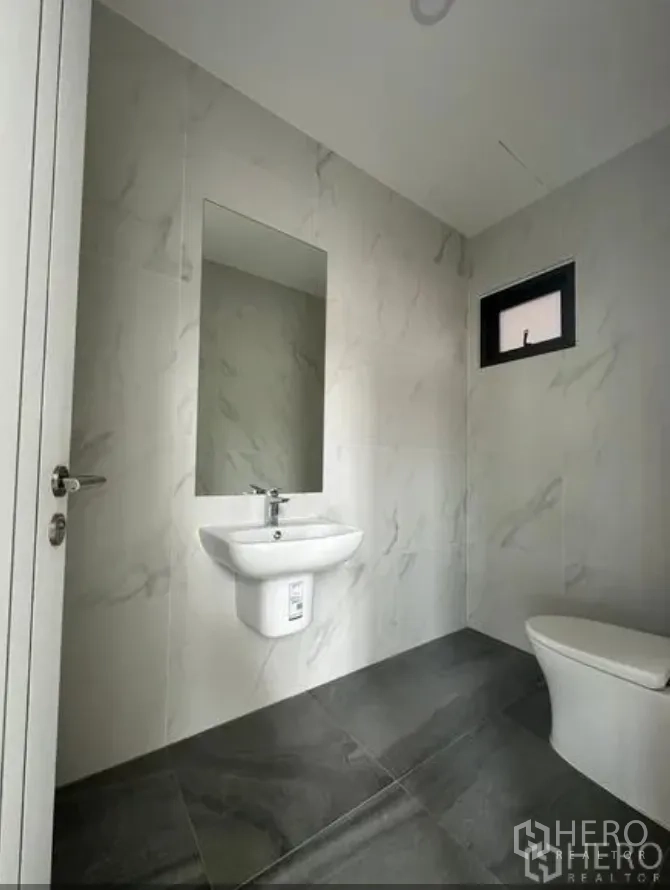 Warehouse for sale in Lam Luk Ka, Pathum Thani - Clean restroom with marble-look wall tiles, wall-hung basin and modern toilet.