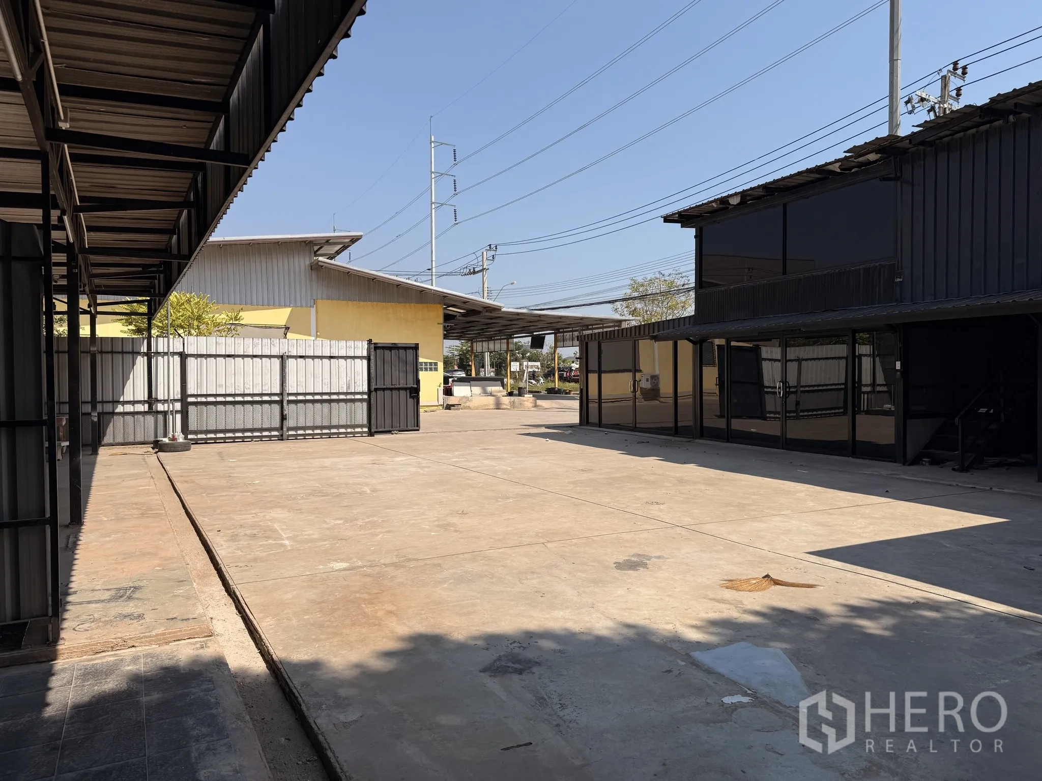 Warehouse for rent in Lat Krabang, Bangkok - Expansive paved yard with glass-fronted office building and covered bays along the perimeter.