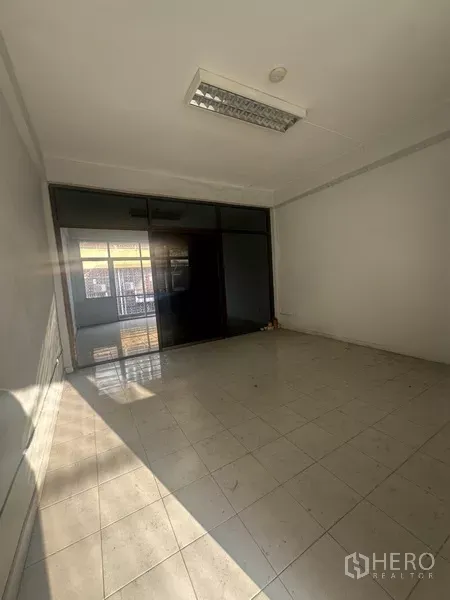 Shophouse for rent in Khlong Toei, Bangkok - Tiled room with large dark glass partition and fluorescent ceiling light.