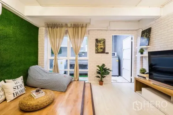独立式住宅 出租在Khlong Toei, Bangkok - 客厅抬高木平台，仿真草墙面与电视柜。