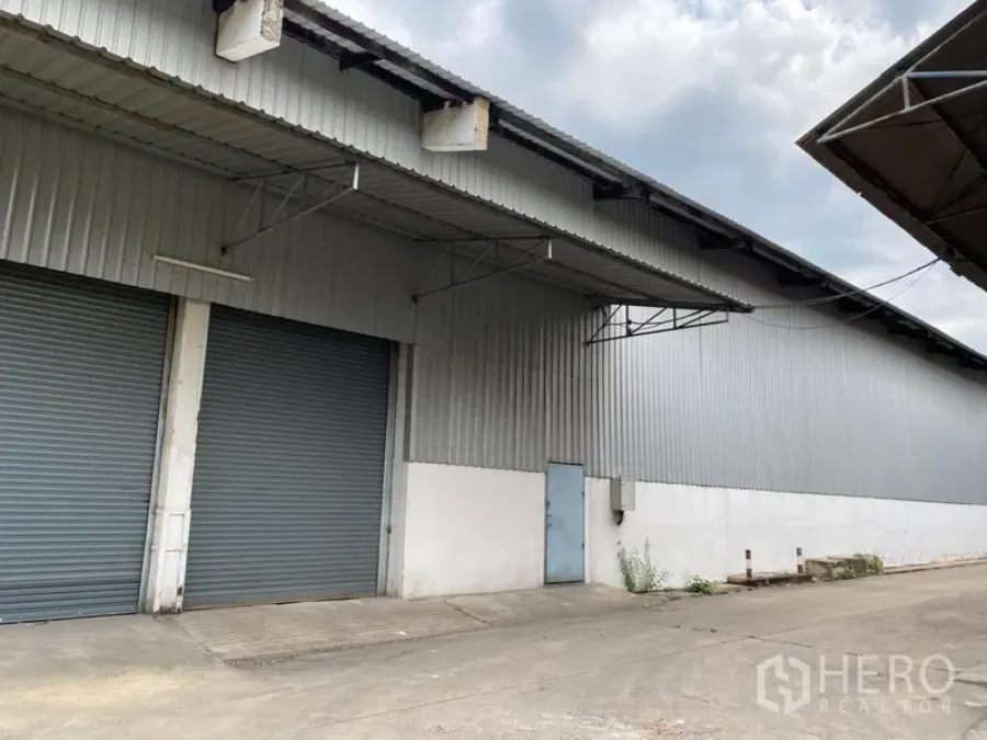 Warehouse for rent in Khlong Luang, Pathum Thani - Metal-clad warehouse exterior with two large roller shutter doors and covered loading canopies.