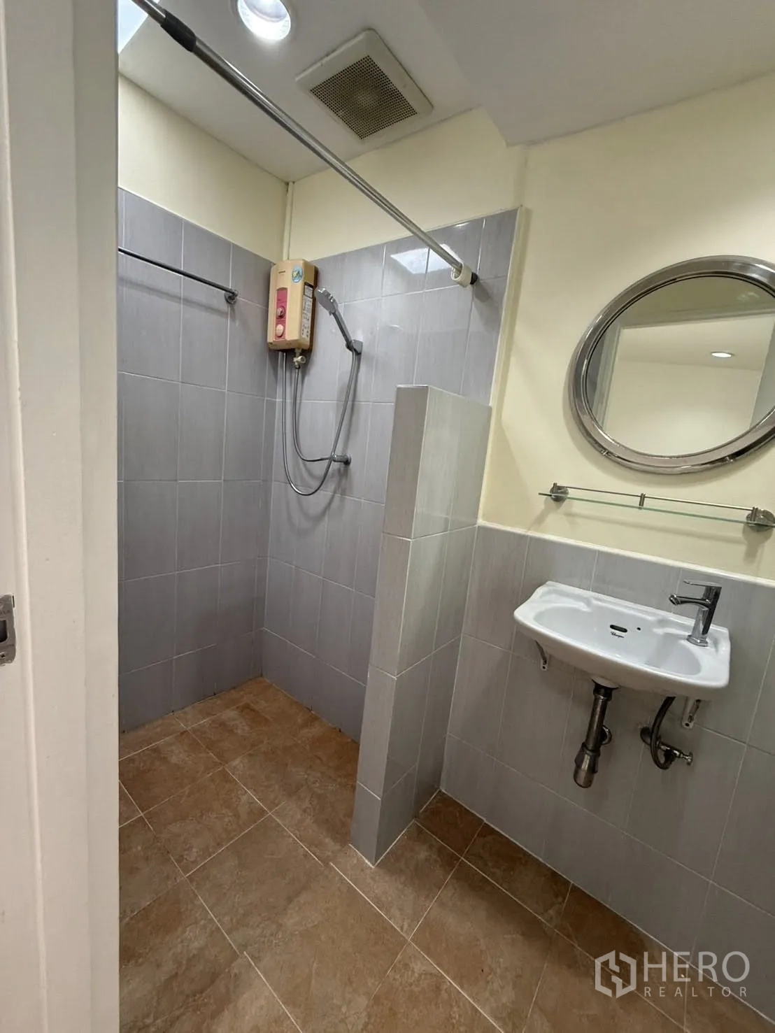 Detached House for rent in Khlong Toei, Bangkok - Second bathroom with a walk-in shower, round mirror, sink, and water heater.