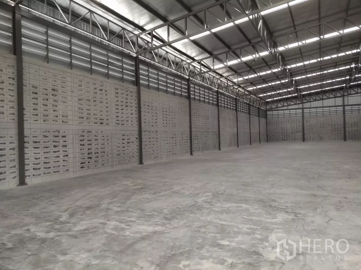 Warehouse for rent in Samut Prakan - Long-span warehouse hall with high ceiling, bright strip lighting and a wide clear floor area.