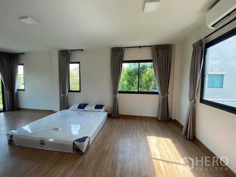 Detached House for rent in Khan Na Yao, Bangkok - Large bedroom with wood floor, multiple windows and garden outlook.