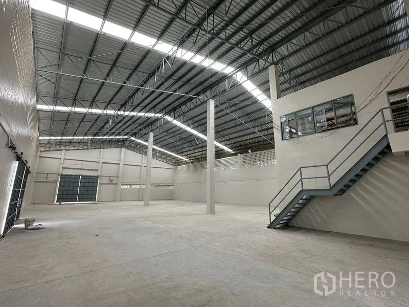 Factory for rent in Lam Luk Ka, Pathum Thani - Production area with mezzanine office windows and metal staircase.