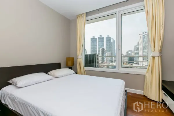 Condominium for rent or sale in Khlong Toei, Bangkok - Bedroom with wide windows showcasing Bangkok city skyline views.
