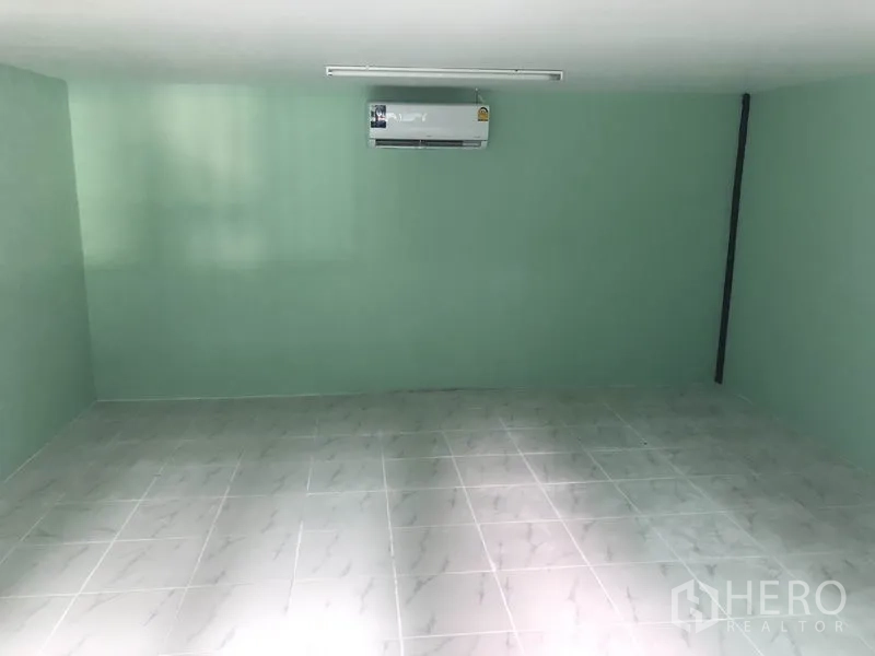 Warehouse for rent in Khlong Luang, Pathum Thani - Air-conditioned office room with tiled flooring and light green walls inside the warehouse.
