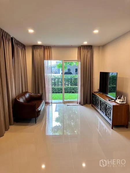 Detached House for sale in Prawet, Bangkok - Lounge facing the garden with sofa, TV and floor-to-ceiling sliding doors.