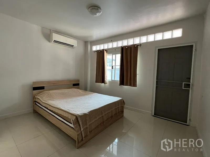 独立式住宅 出租在Bang Kapi, Bangkok - 卧室带外门与高侧窗，配空调与简约装饰。