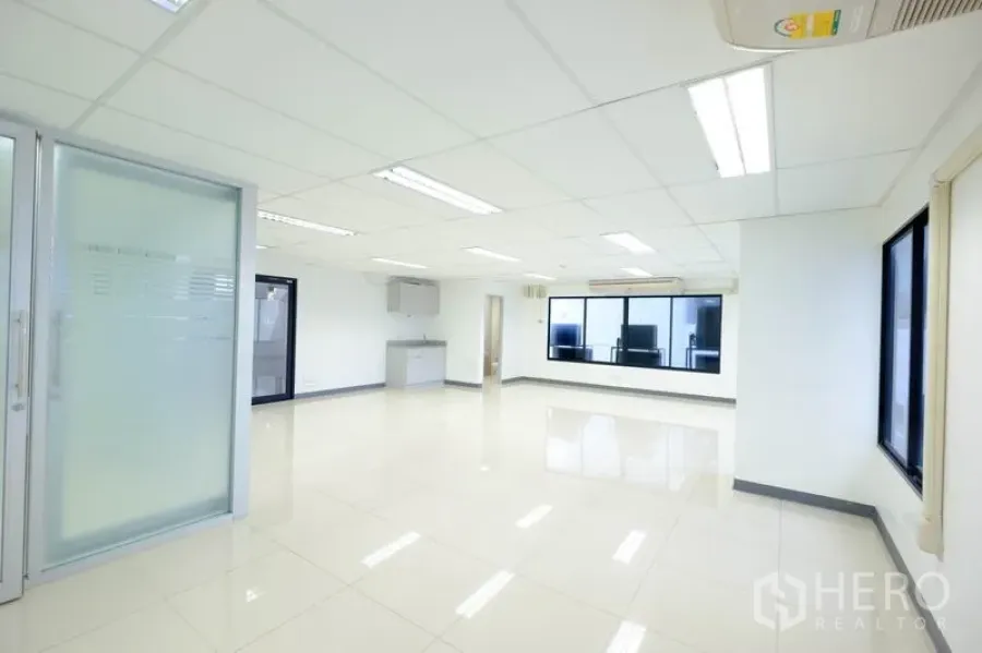 Office Space for rent in Chatuchak, Bangkok - Corner office view with large windows, sliding frosted-glass door, pantry and air-conditioning.